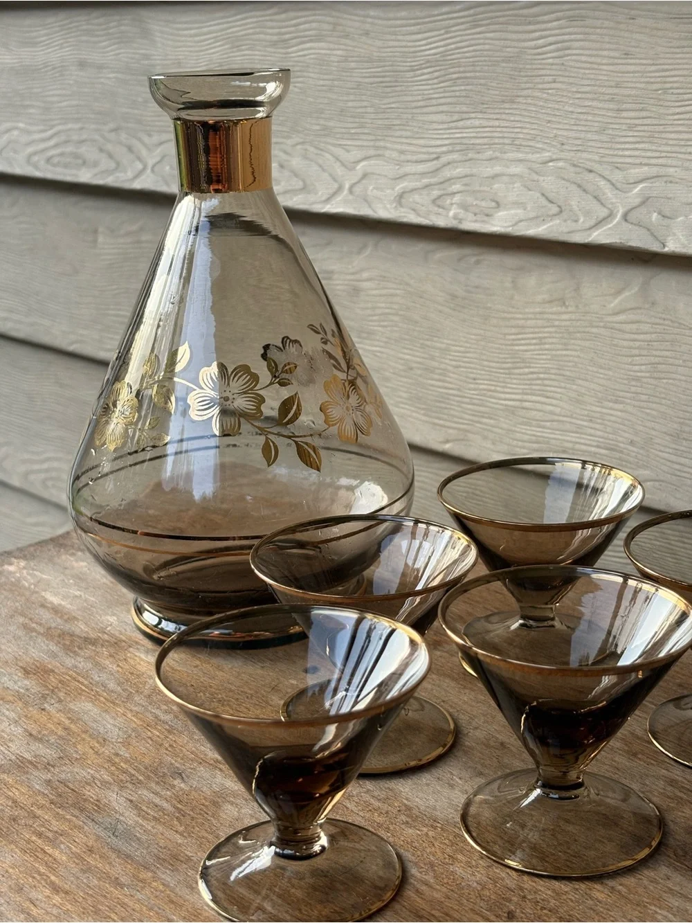 Art Deco decanter set features smoky purple glass adorned with a gold floral